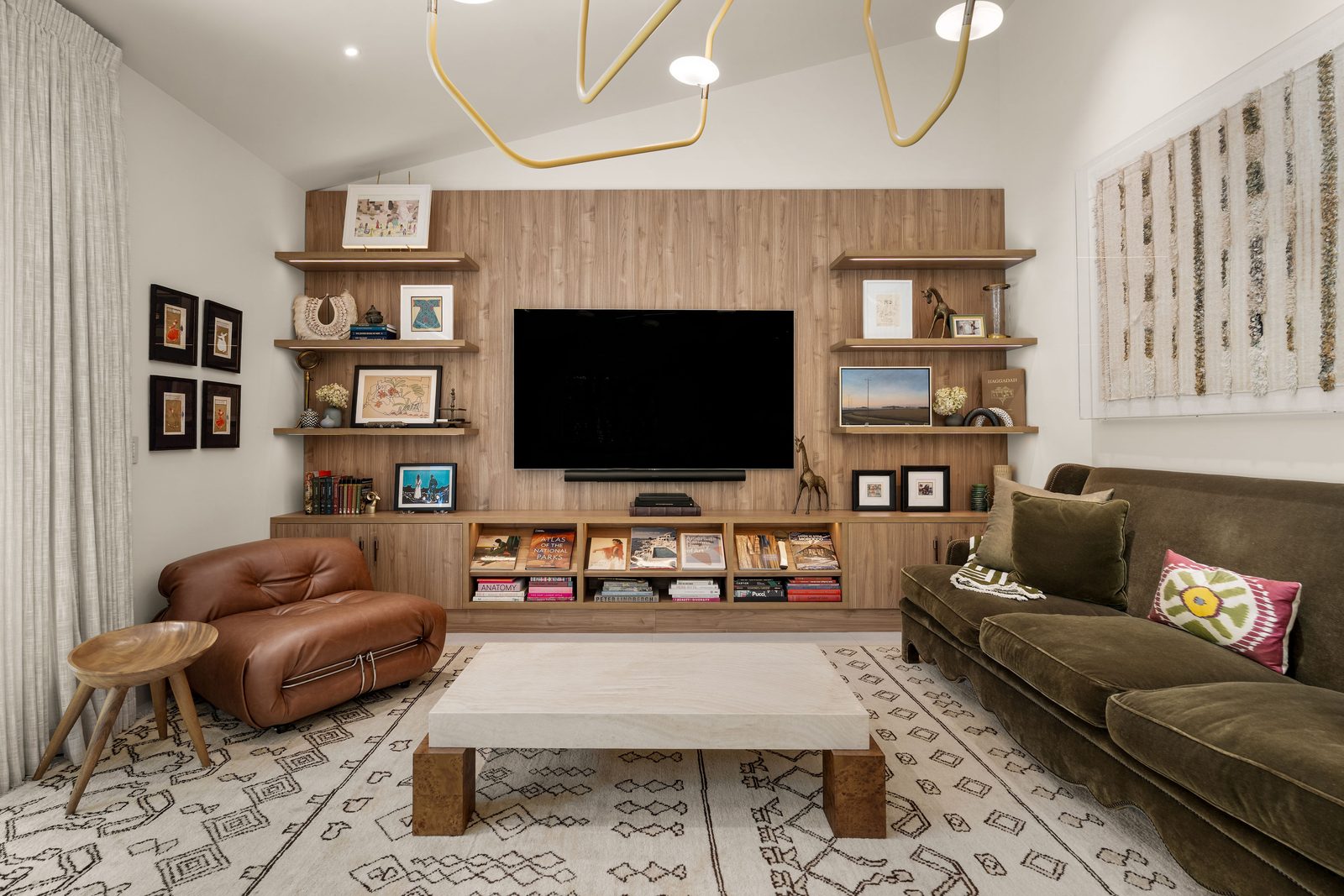 Custom wood media wall with floating shelves and open storage below, in a family room